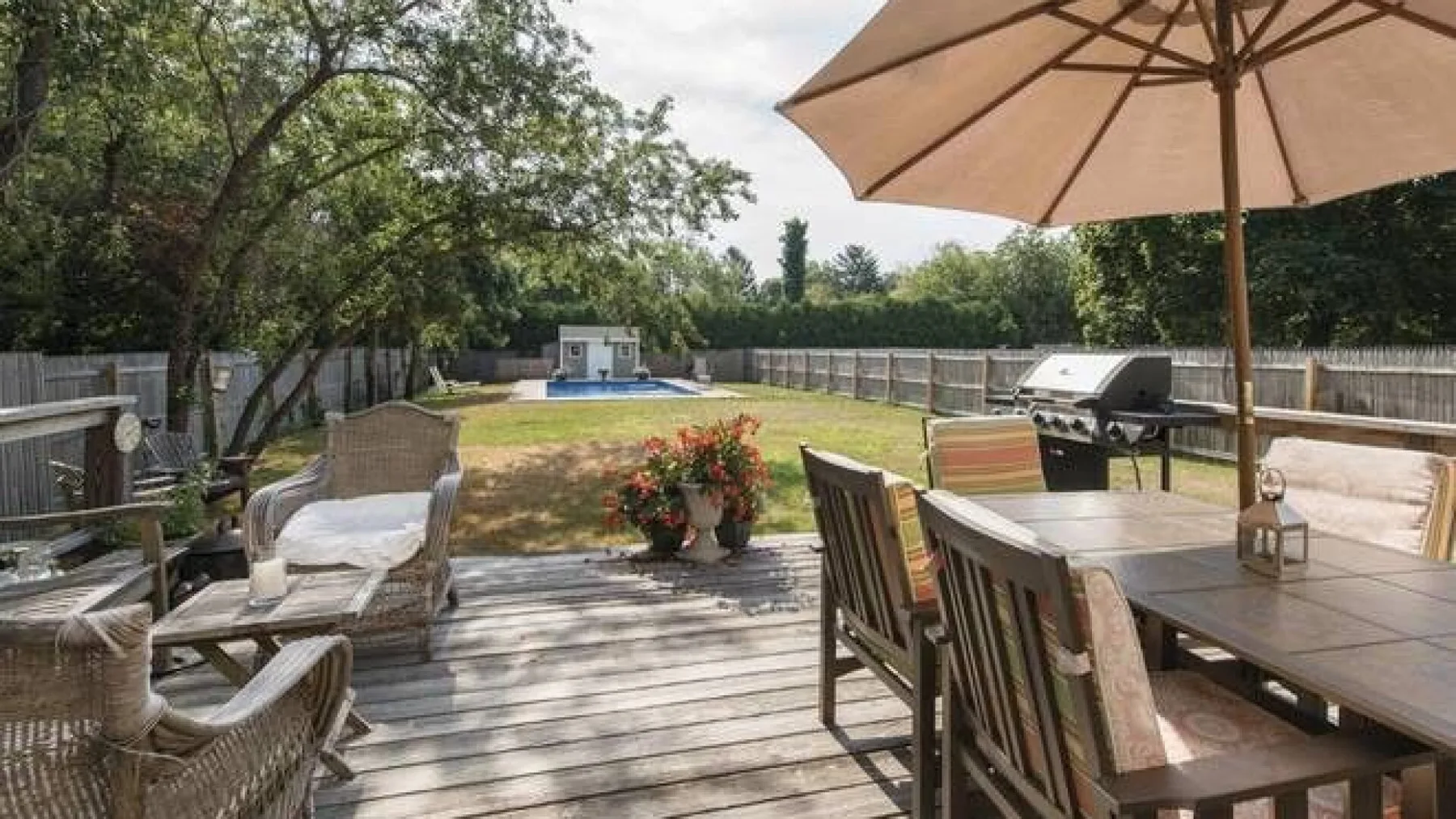 Un patio trasero con asientos al aire libre, una sombrilla y una piscina.