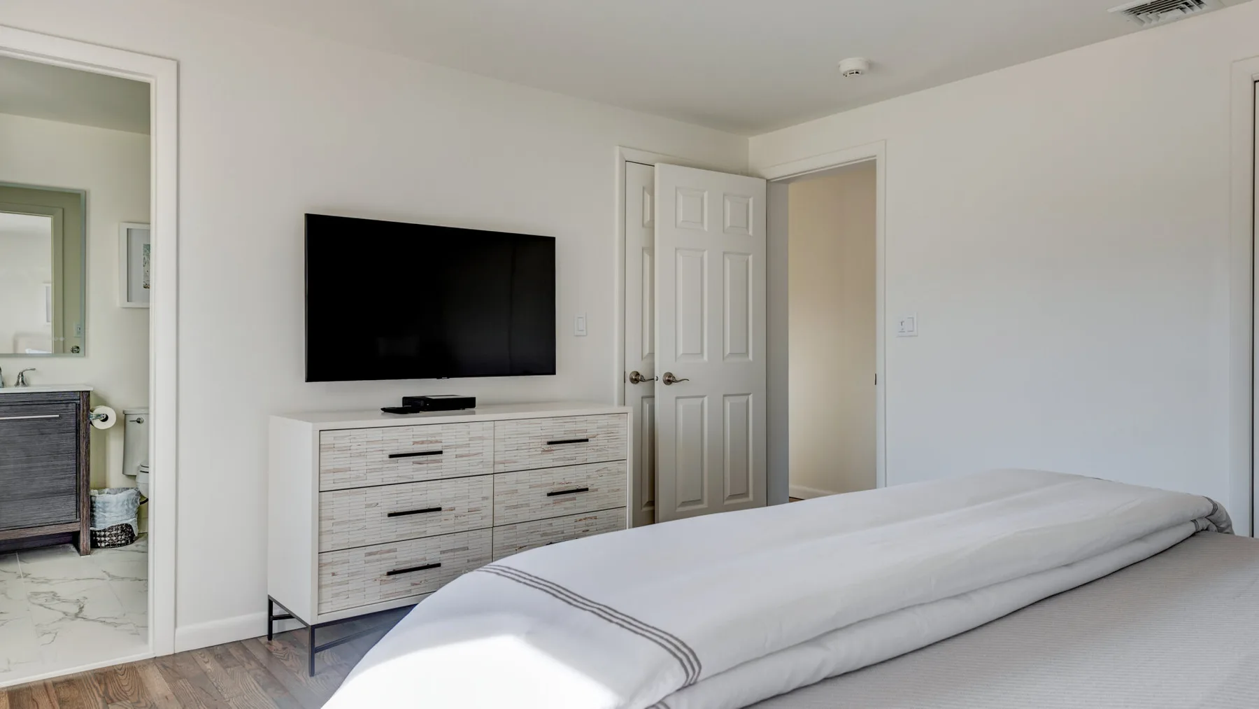 Un dormitorio con una cama bien tendida y un televisor sobre una cómoda.