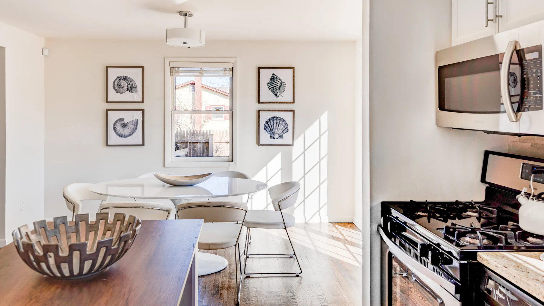 Un comedor luminoso y una cocina con mesa, sillas y estufa.