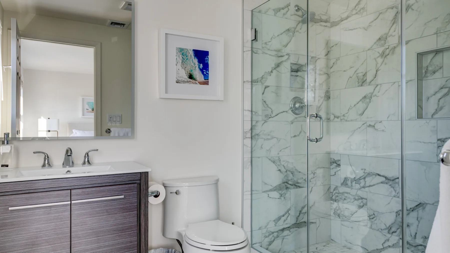 Un baño con lavabo, inodoro y ducha con mampara de vidrio.