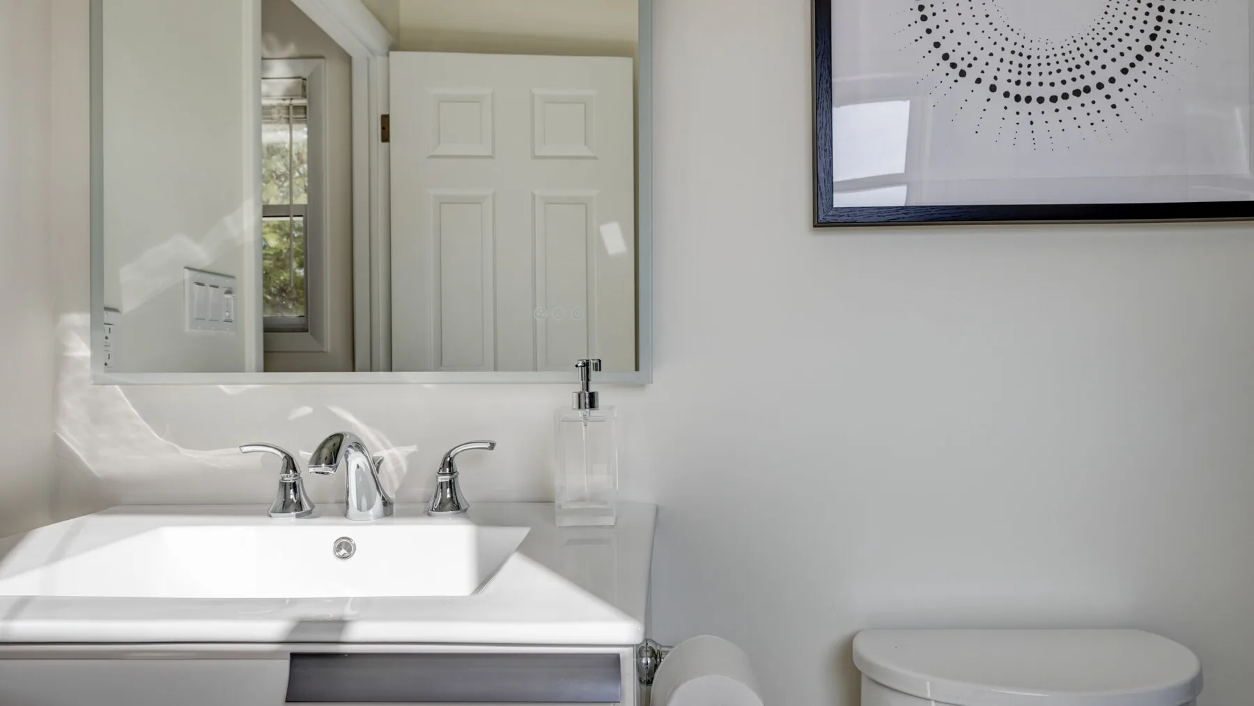Un lavabo y un inodoro están bajo un gran espejo de pared.