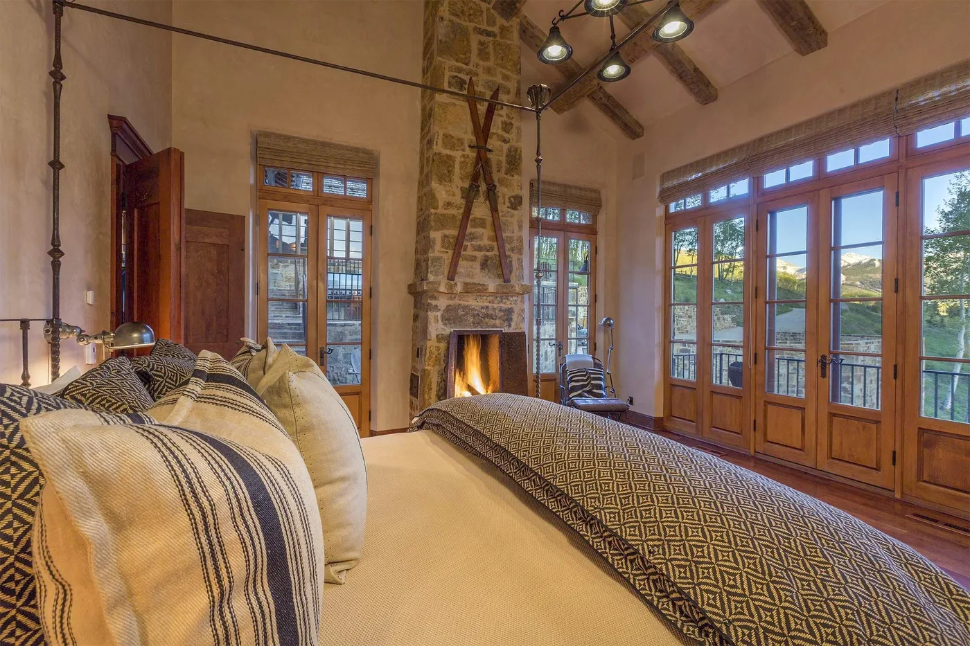 Un dormitorio con una cama grande, una chimenea de piedra y ventanas altas.