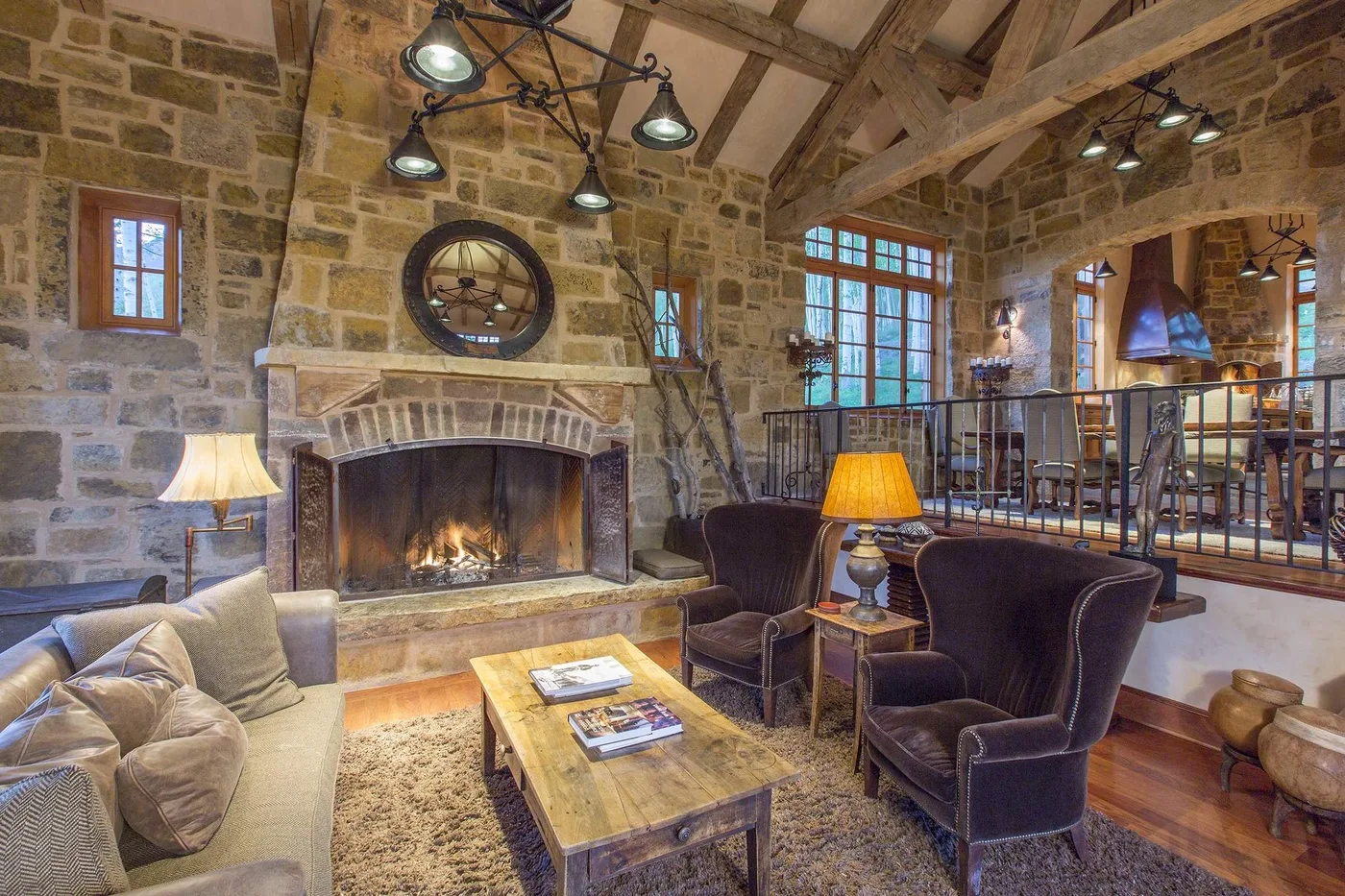 Una sala de estar de piedra con chimenea, asientos y una mesa de centro de madera.