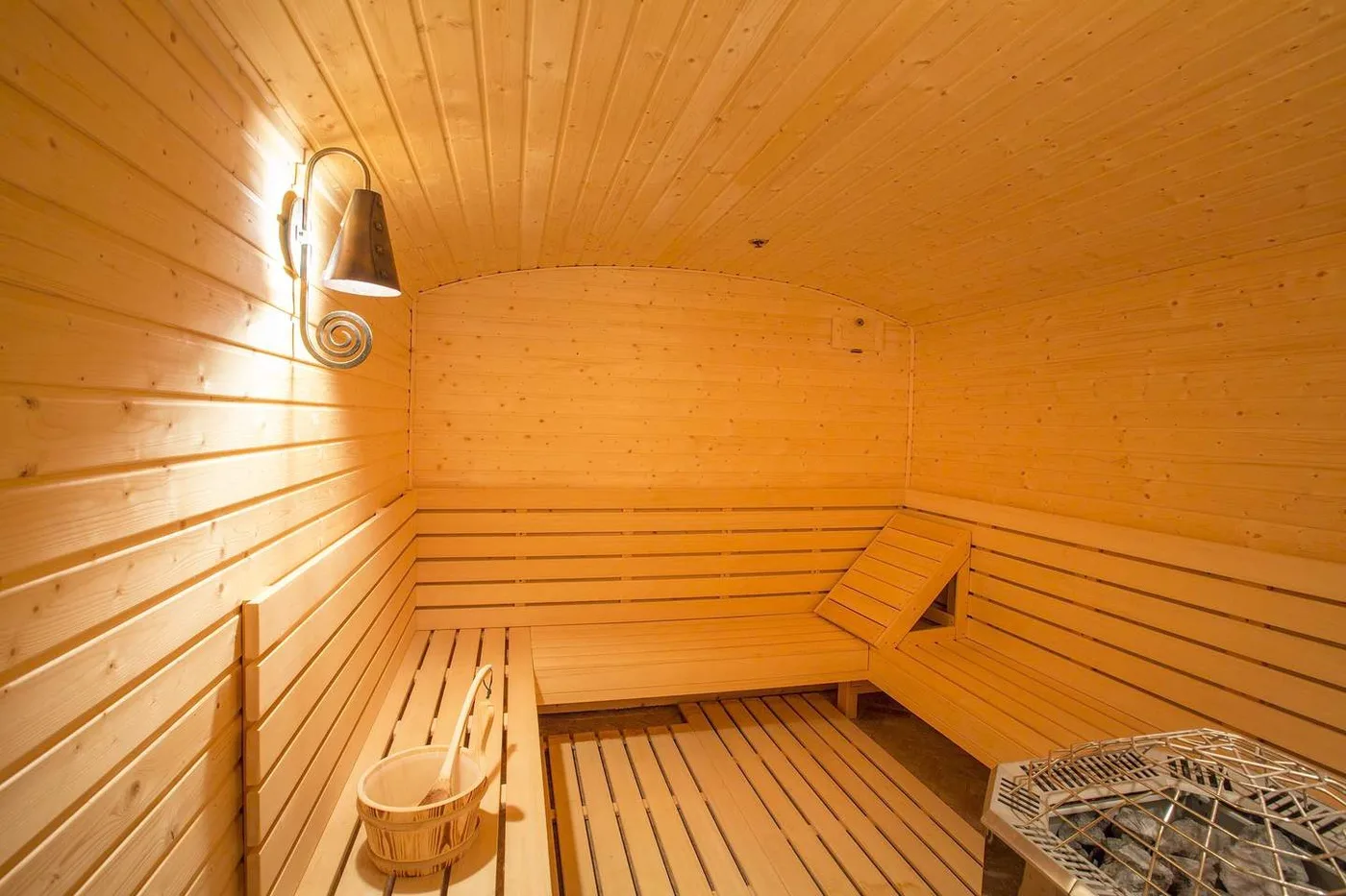 Una sauna revestida de madera con bancos escalonados y un calentador.