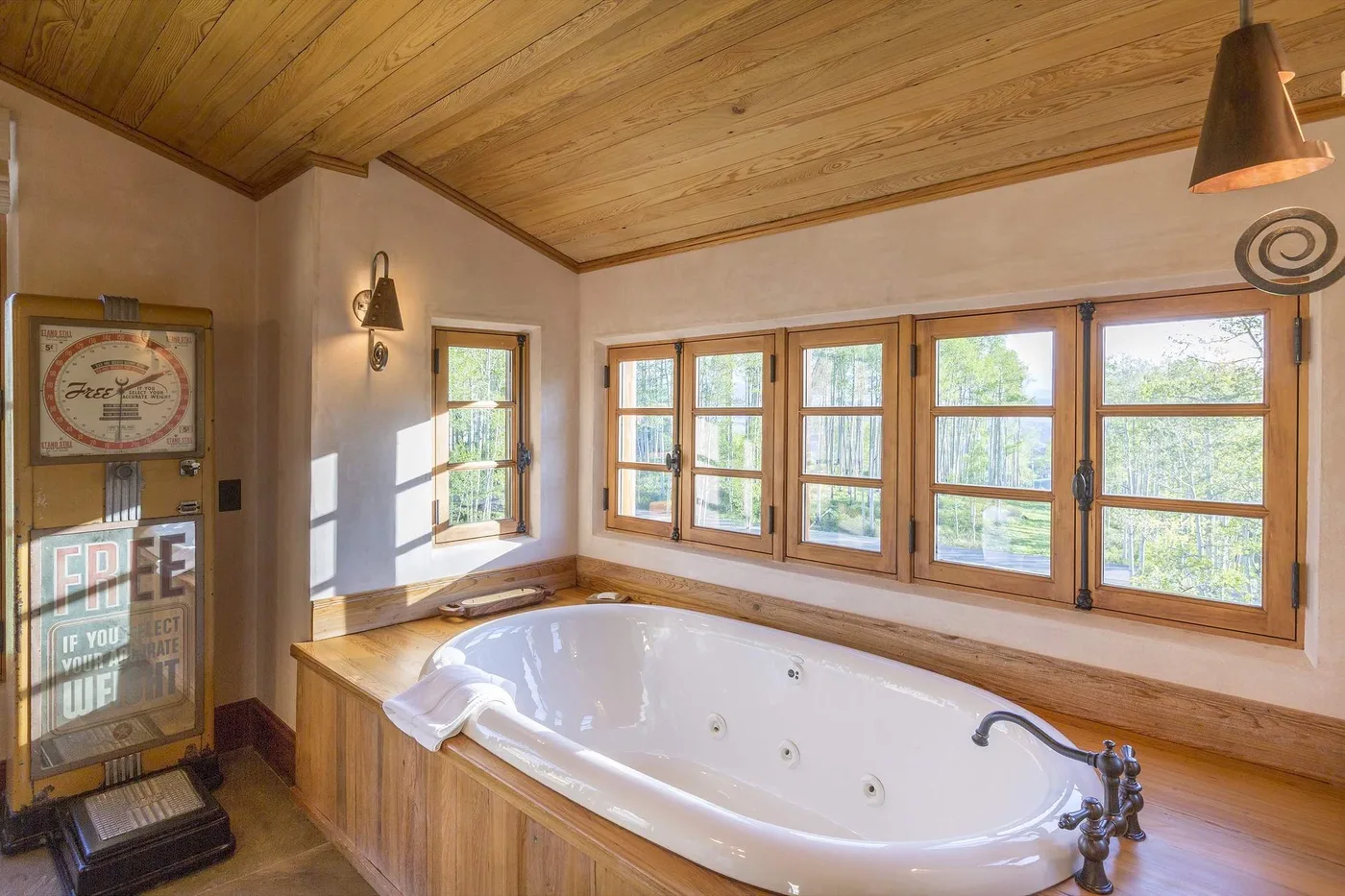 Un baño con una bañera grande bajo una fila de ventanas.