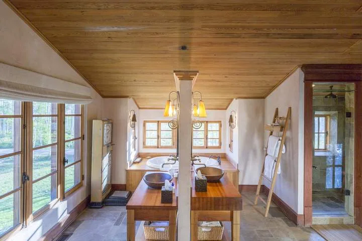 Un baño con muebles de madera, lavabos y una ducha con mampara de vidrio.