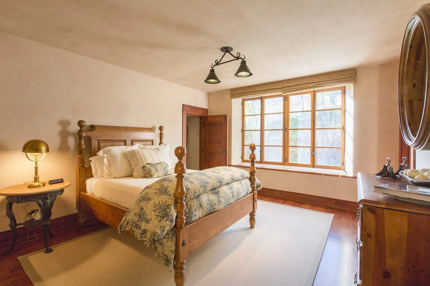 Un dormitorio con una cama de madera y ventanas grandes que dejan entrar la luz.