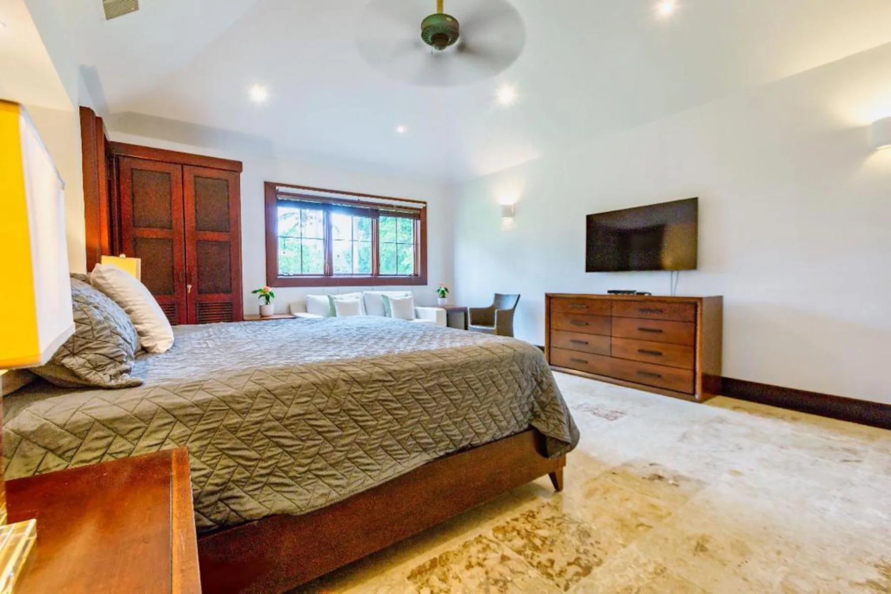 Un dormitorio con una cama grande, una ventana y una cómoda de madera.