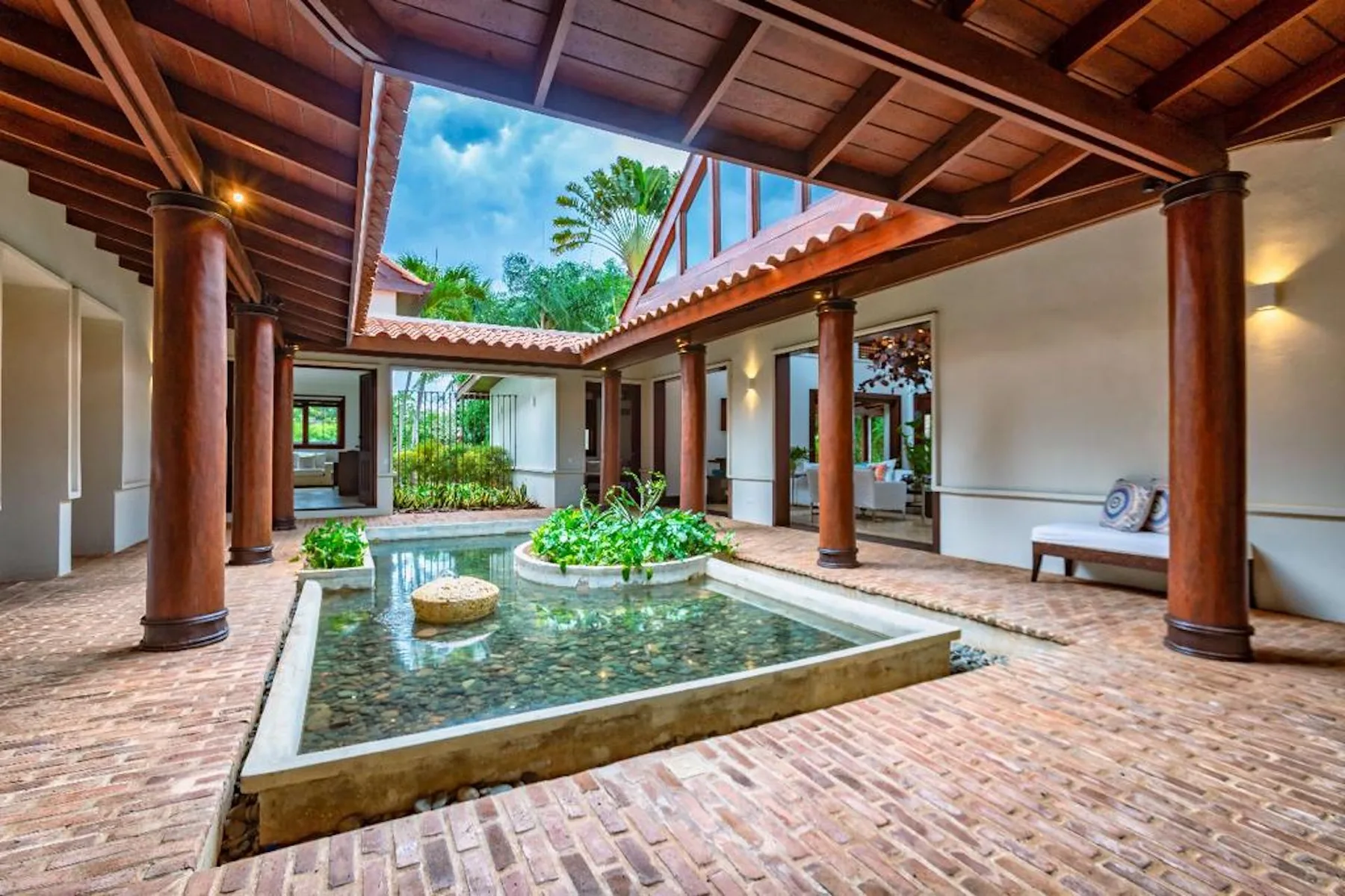 Un patio cubierto con una piscina poco profunda y columnas alrededor.