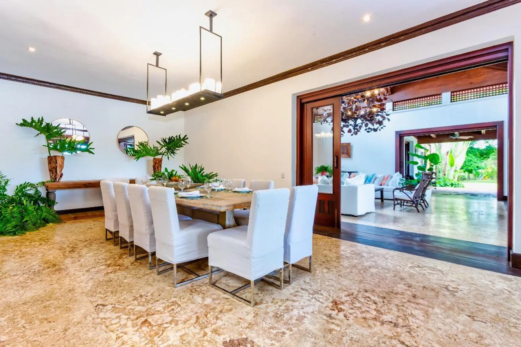 Comedor con una mesa larga y asientos tapizados junto a una sala de estar abierta.