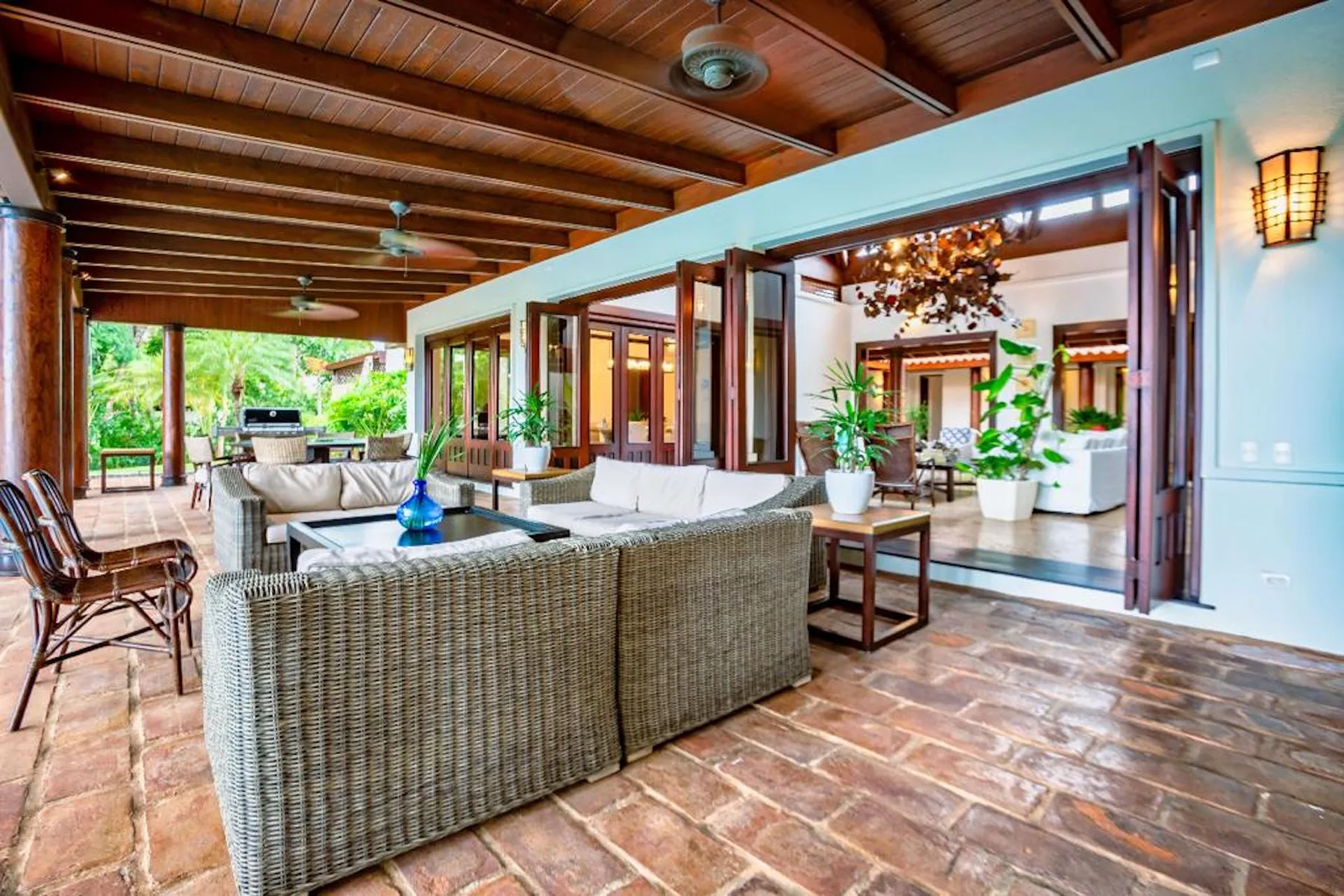Un amplio patio cubierto con asientos de mimbre y vistas abiertas a una habitación contigua.