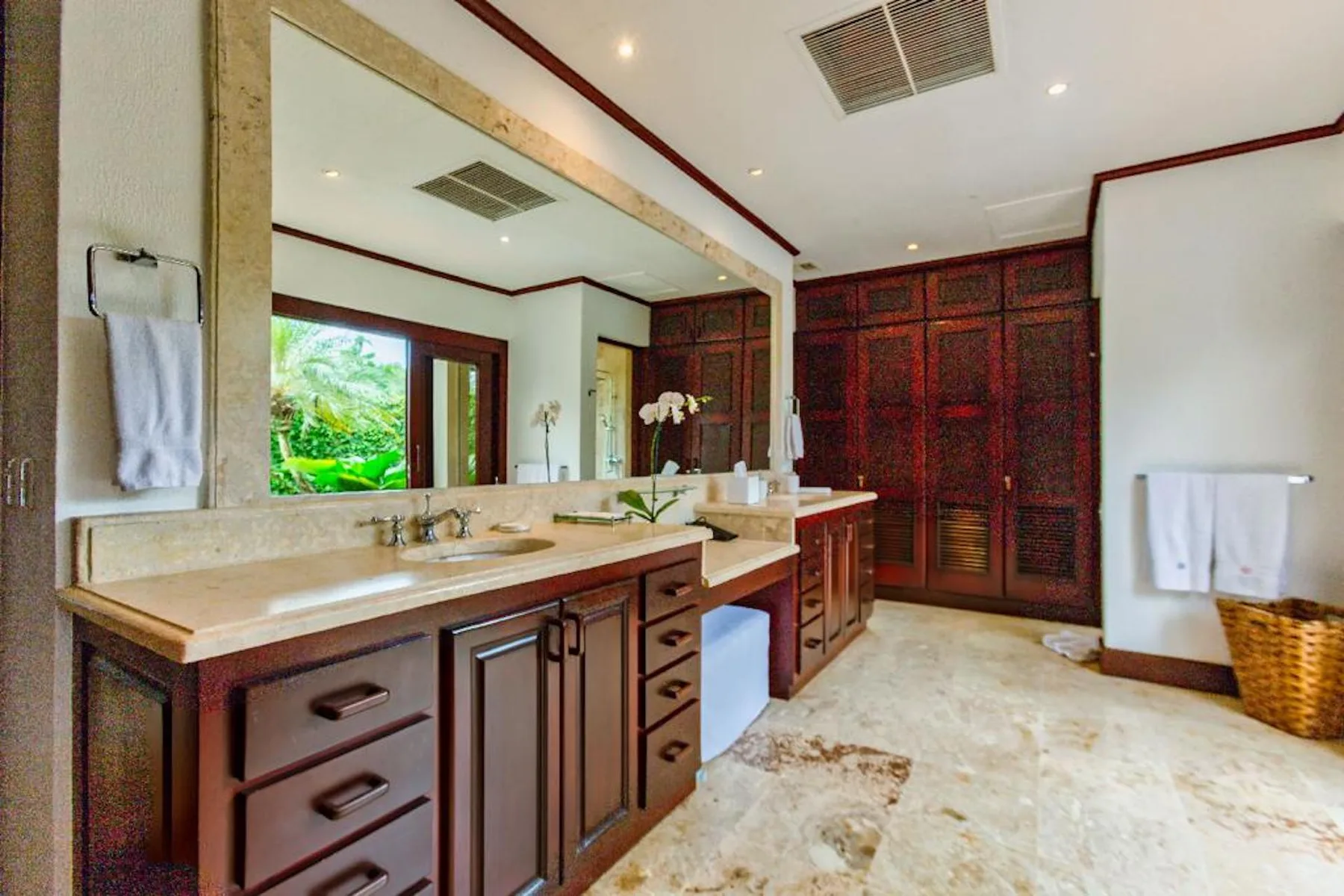 Un baño amplio con un tocador largo, un espejo grande y gabinetes de madera oscura.