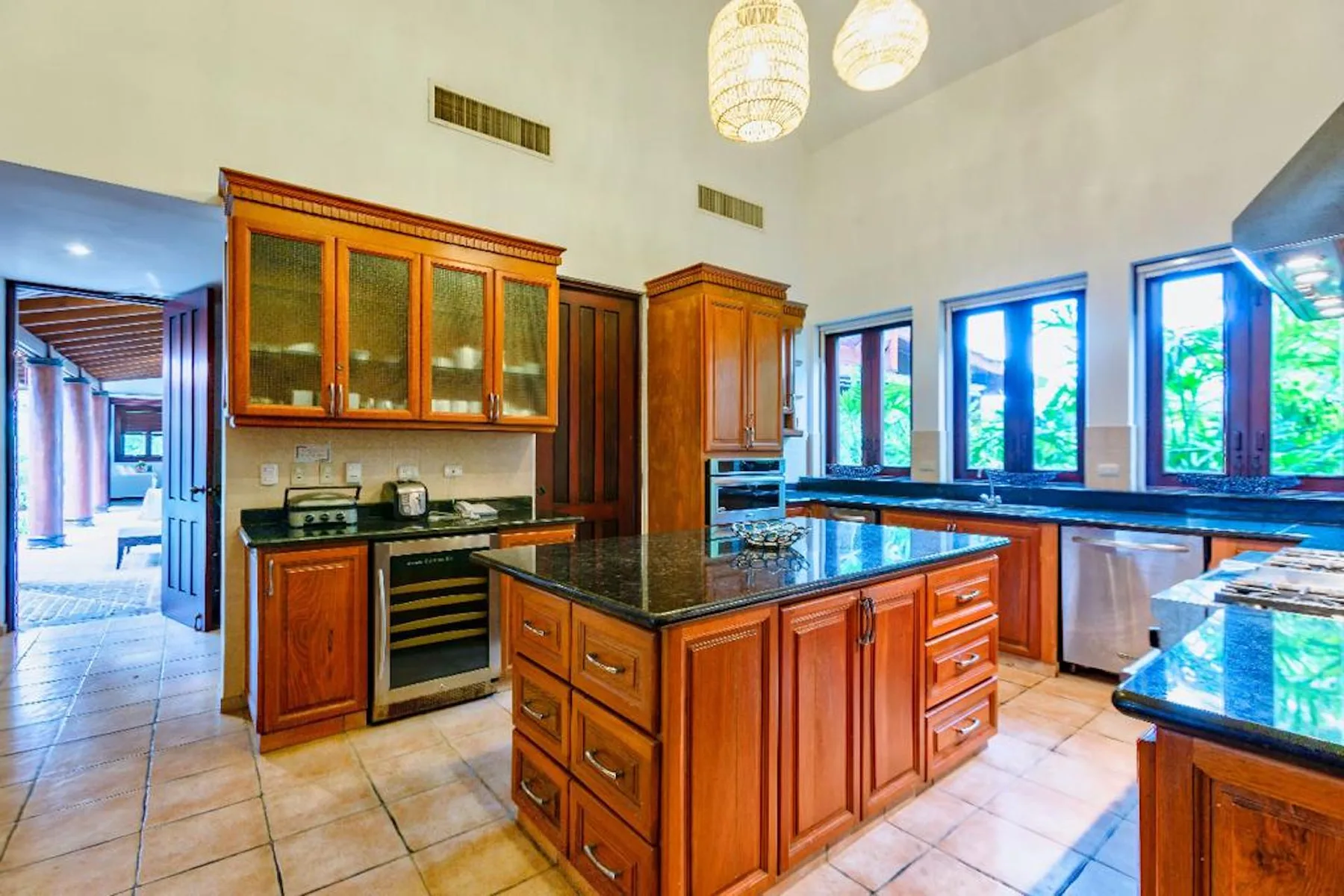 Una cocina amplia con gabinetes de madera, encimeras oscuras y ventanas grandes.