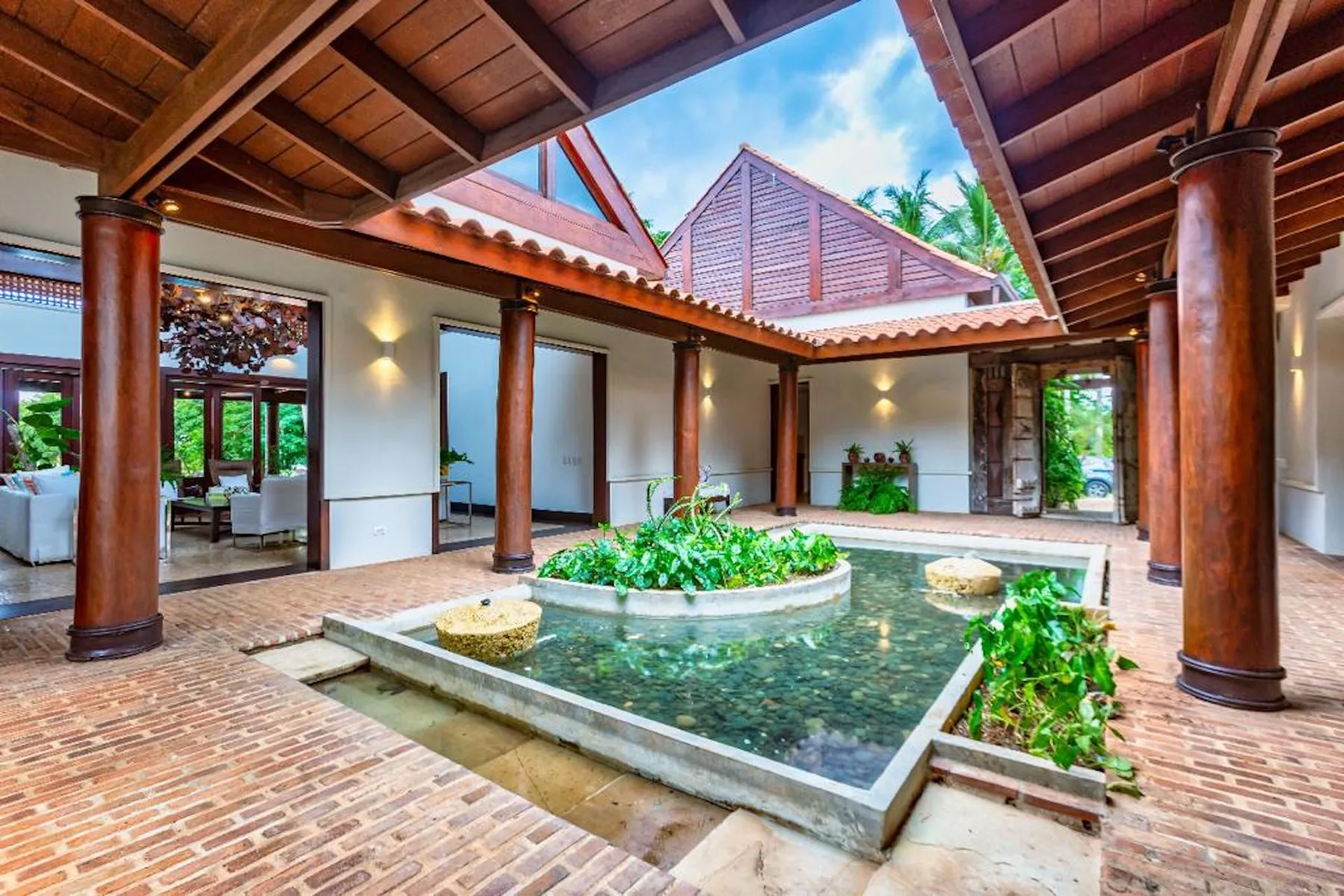 Un patio al aire libre cuenta con una piscina poco profunda y una fuente central con plantas.