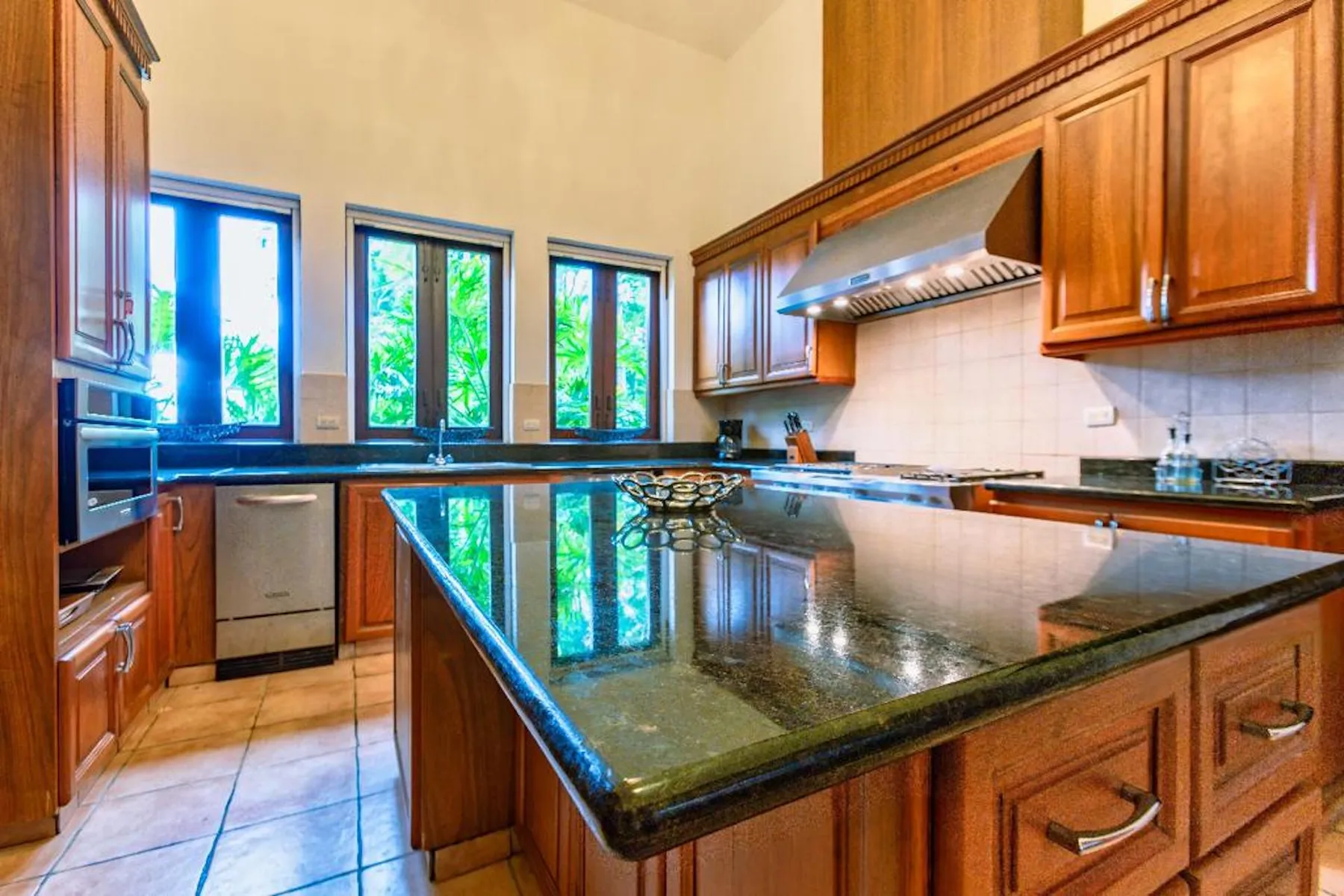 Una cocina amplia con gabinetes de madera, una isla grande y ventanas altas.