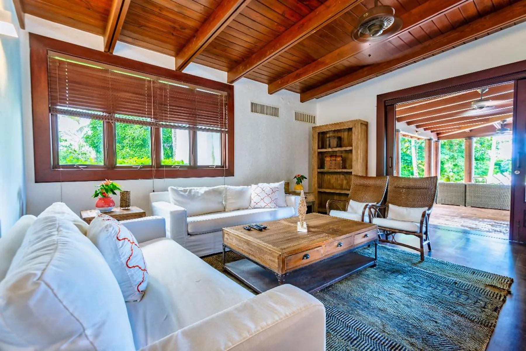 Una sala de estar con asientos blancos, una mesa de centro de madera y un techo de madera.