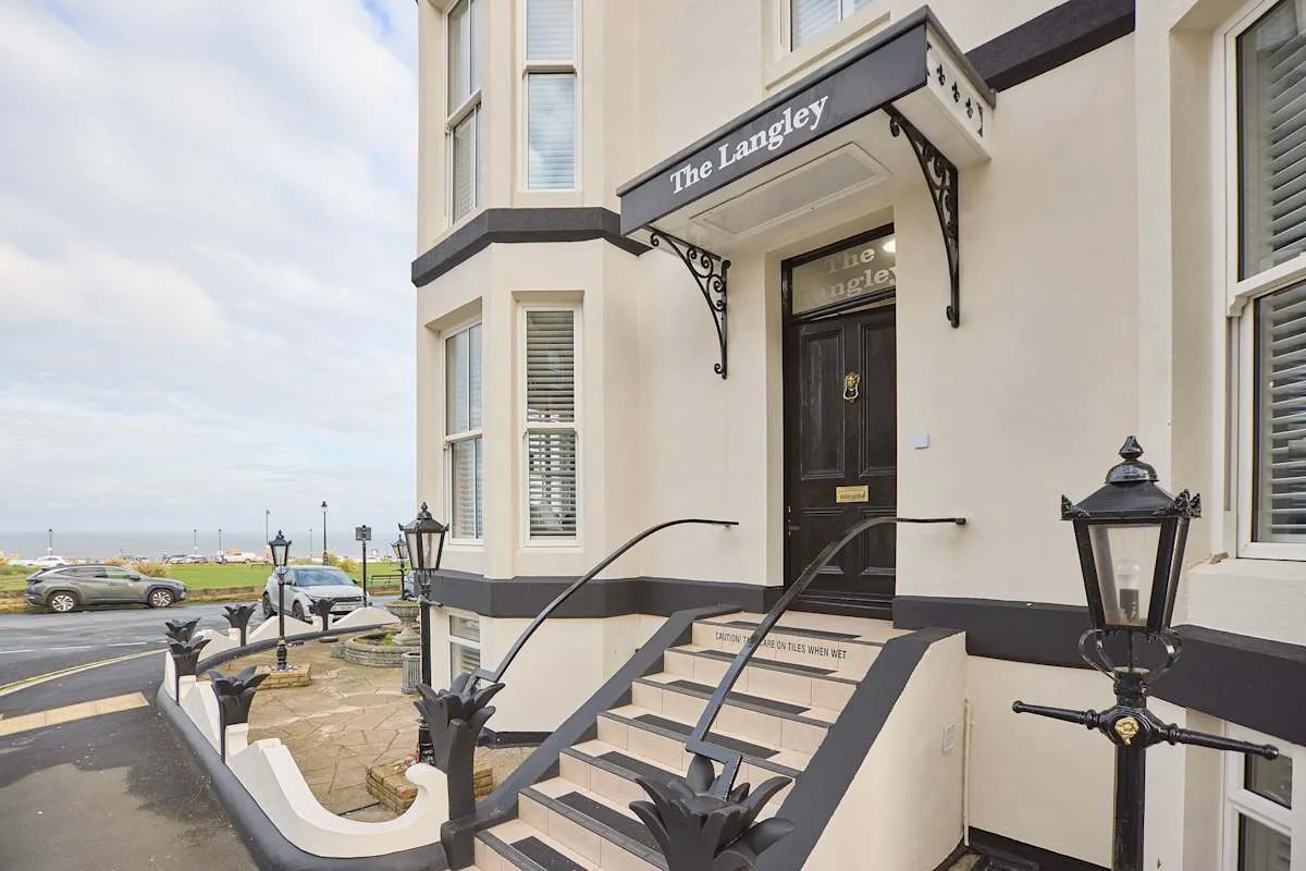 Hotel entrance with steps leading to a dark front door beneath a sign.
