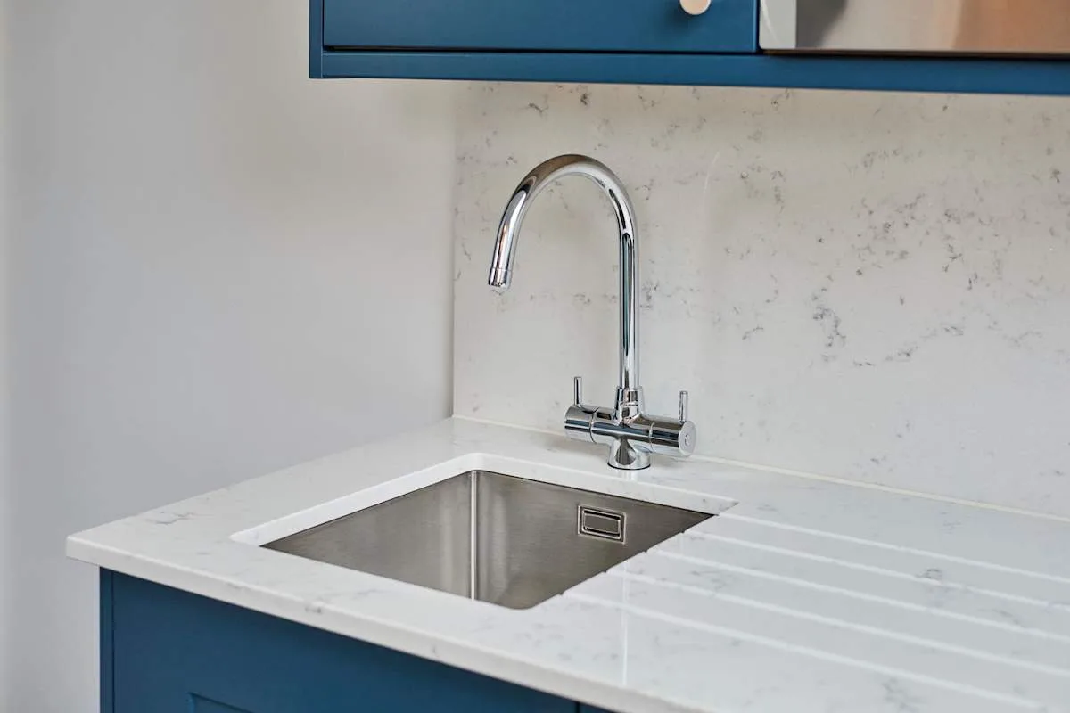 A kitchenette with a stainless-steel sink and blue cabinetry.