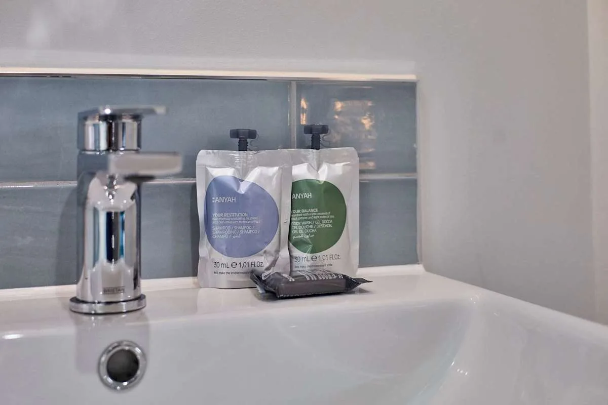 A bathroom sink with a chrome faucet and toiletry packets on the ledge.