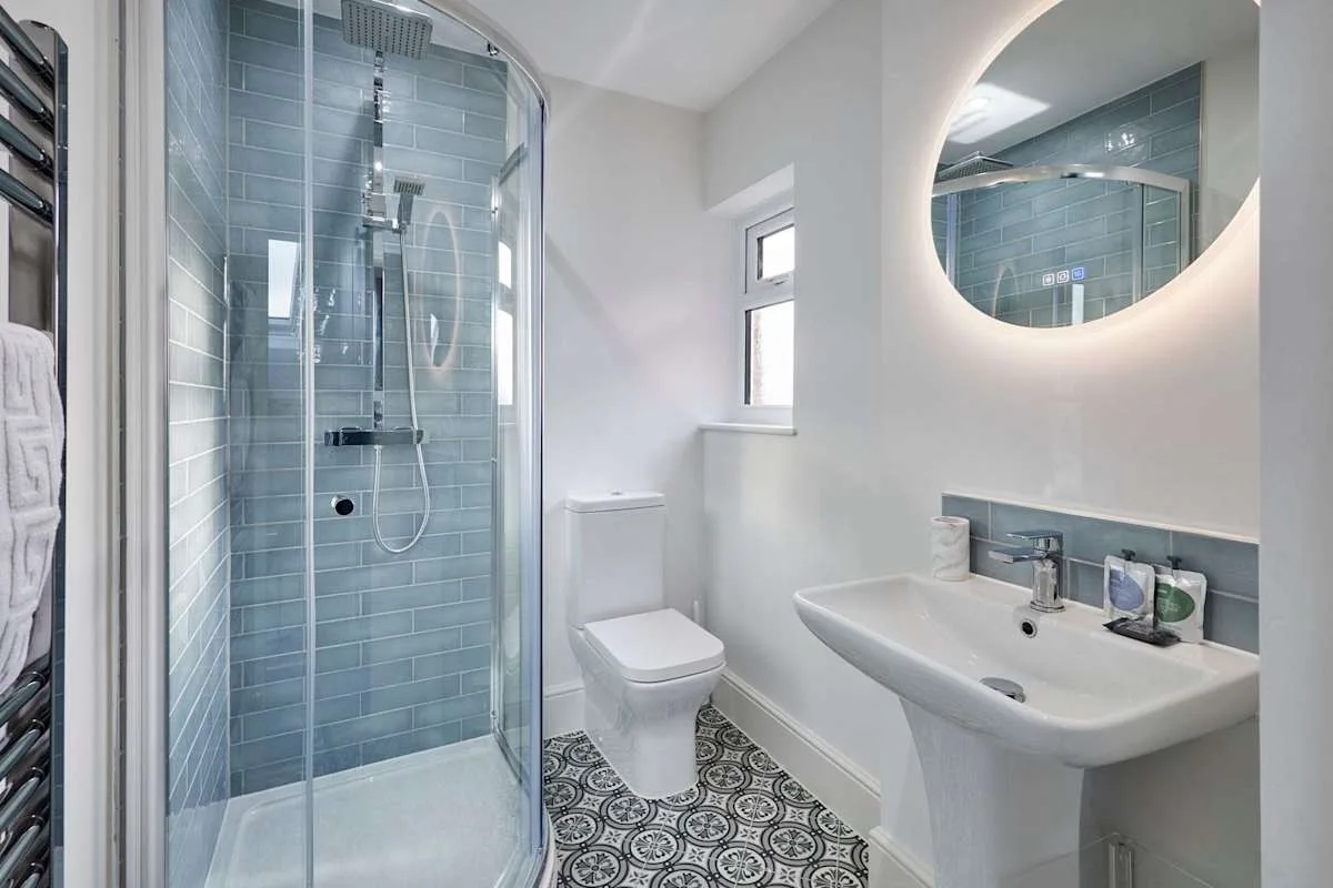 A modern bathroom with a glass shower, toilet, and sink.