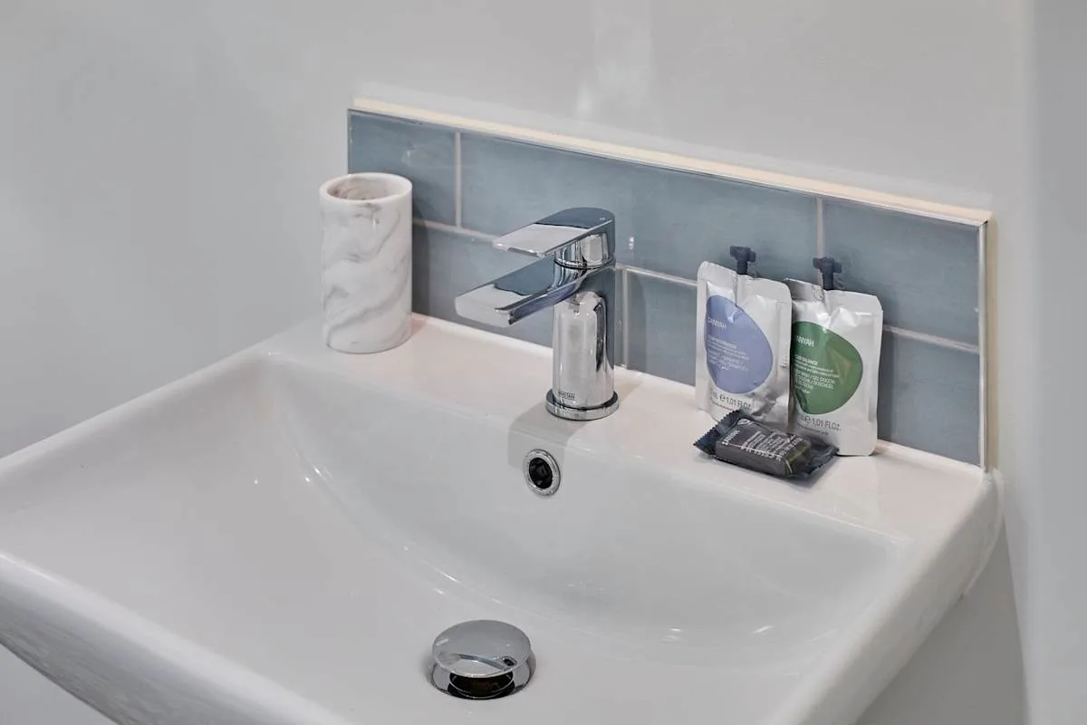 A bathroom sink with a chrome faucet and toiletries on the ledge.