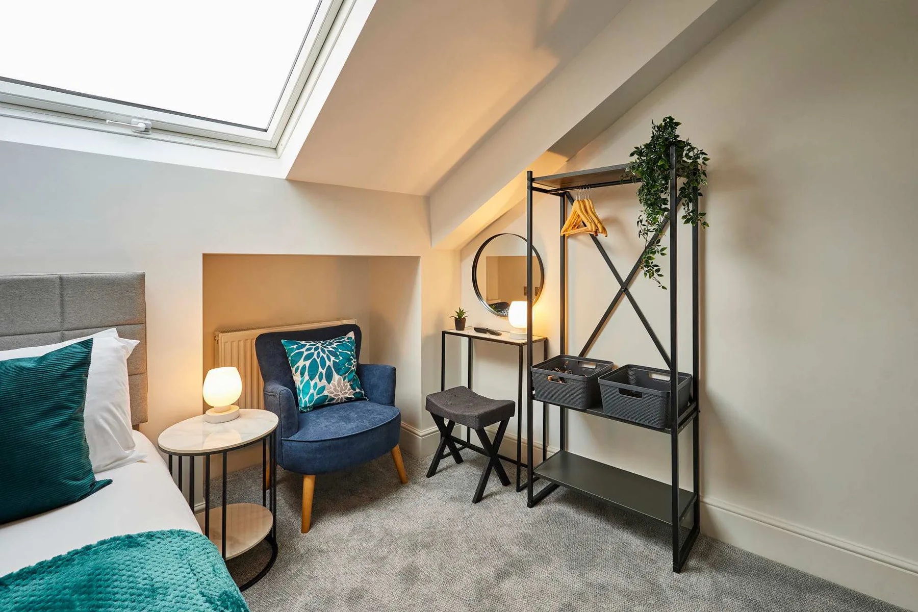 A bright bedroom with a bed, an armchair, and a skylight.