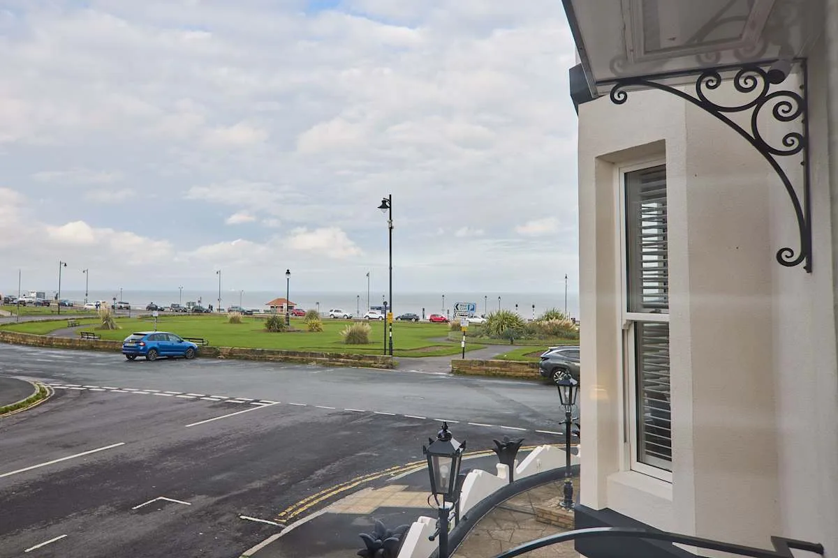A street view shows a road, a grassy area, and the waterfront in the distance.