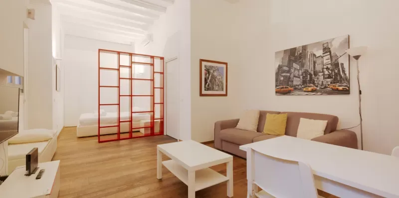 A bright living area with seating, a dining table, and a red-framed divider.