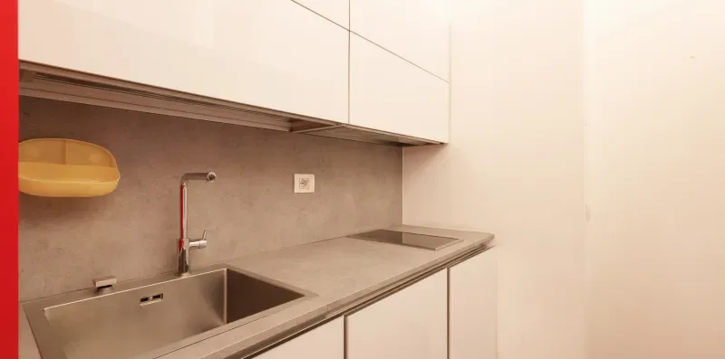 A modern kitchen counter with a sink, faucet, and cooktop.