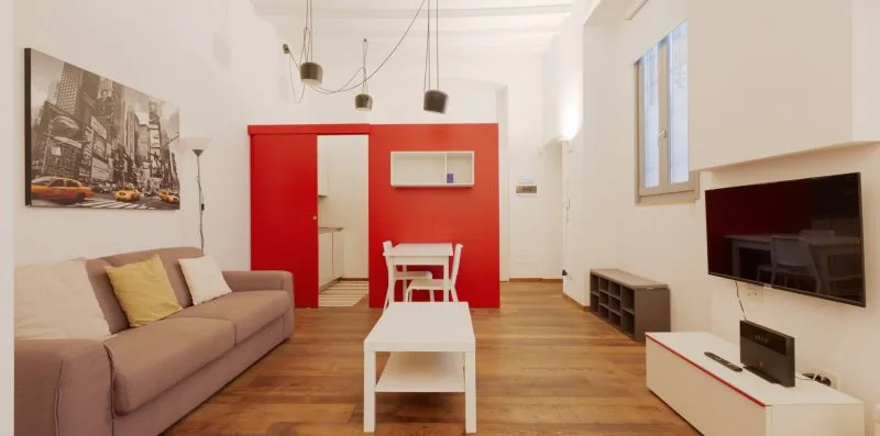 A bright living room with seating, a coffee table, and a wall-mounted television.