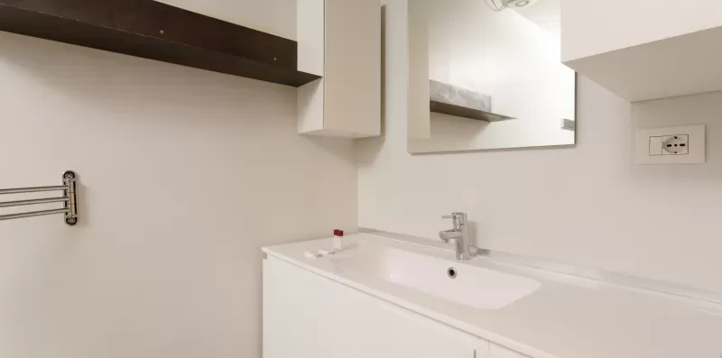 A bathroom vanity with a sink, faucet, and wall mirror.