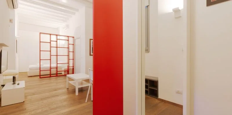 A bright living area with a red divider and light wood flooring.