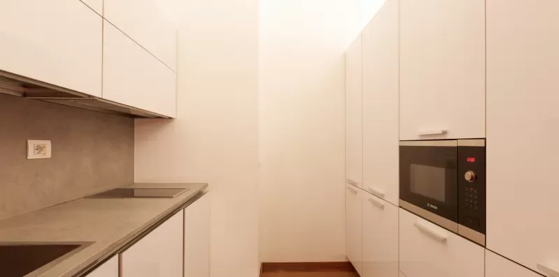 A modern kitchen with pale cabinetry and built-in appliances.