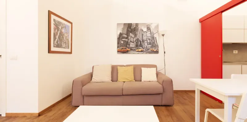 A living room with a sofa, wall art, and a white table.