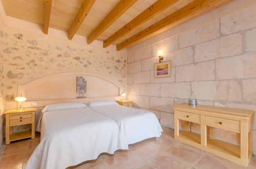 Un dormitorio con cama doble, mesillas de madera y vigas a la vista en el techo.