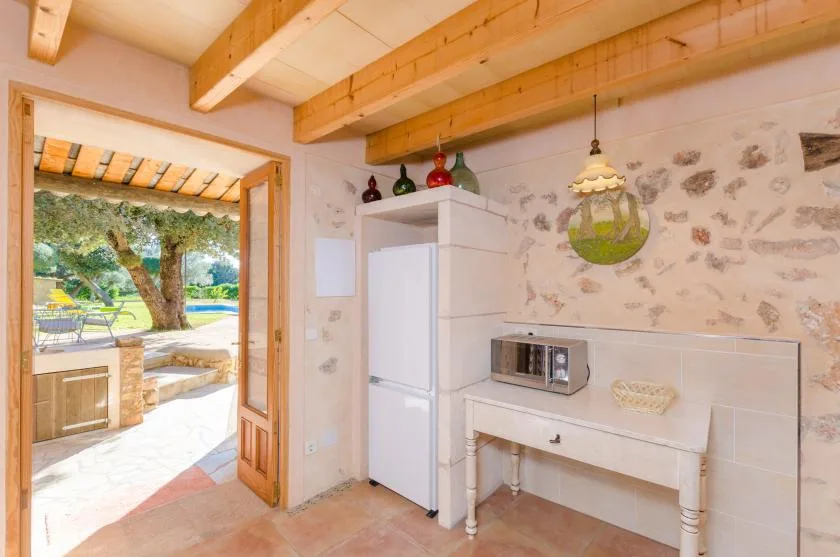 Una cocina con refrigerador y encimera, abierta a un patio exterior.
