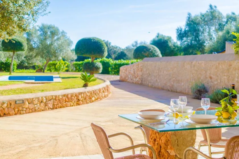 Un patio exterior soleado con una mesa de comedor junto a un jardín.