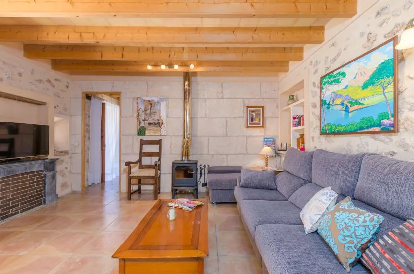 Una sala de estar con asientos grises, una mesa de centro de madera y un cuadro de paisaje.