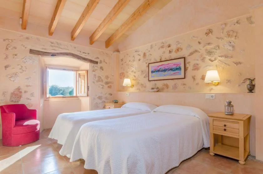 Un dormitorio con dos camas, papel tapiz floral y vigas de madera expuestas en el techo.
