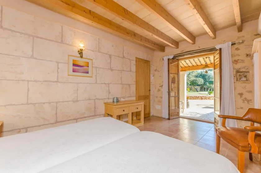 Un dormitorio con camas, techo de madera y una puerta abierta a un patio.
