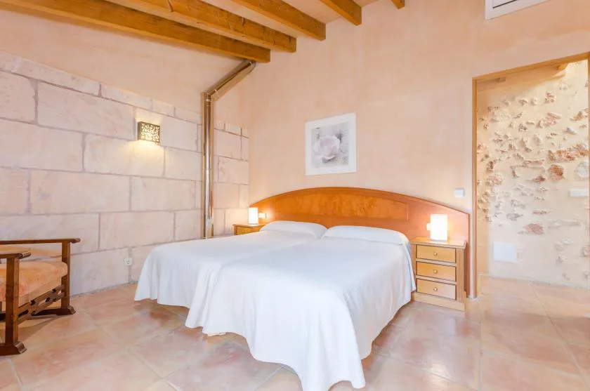 Un dormitorio con dos camas vestidas de blanco junto a un cabecero de madera.