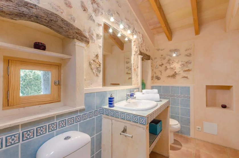 Un baño con un lavabo alicatado, espejo y ventana pequeña.