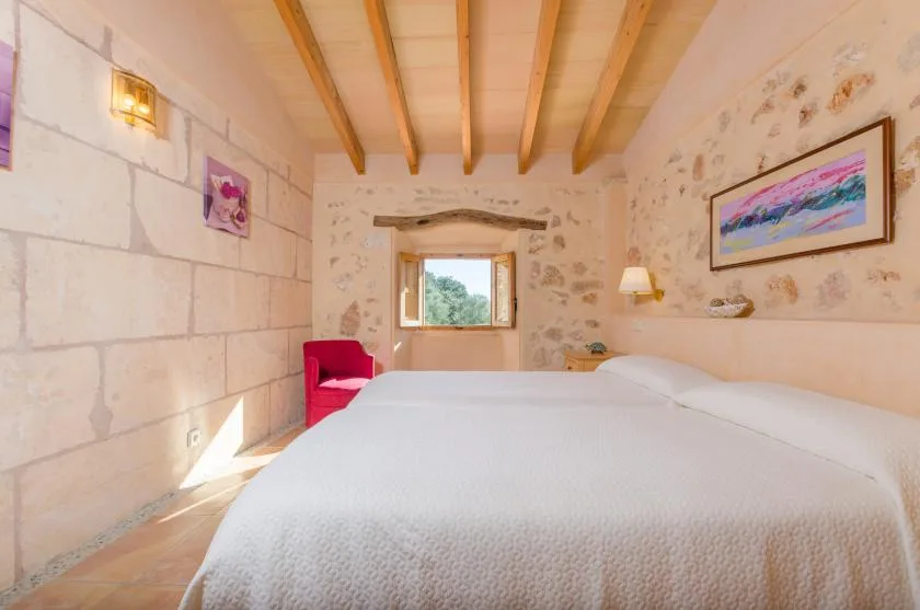 Un dormitorio con una cama grande, vigas de techo expuestas y una ventana.