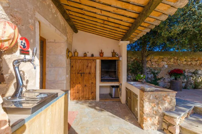 Una zona de cocina exterior cubierta con un armario de madera y una parrilla empotrada.