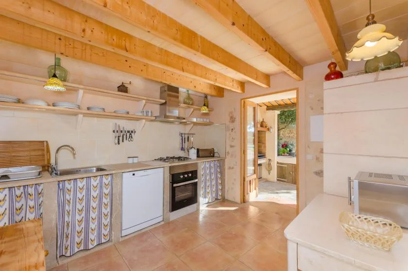 Una cocina luminosa con una encimera larga y vigas de madera a la vista.