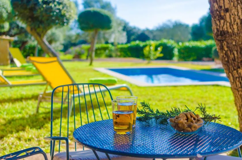 Una zona de descanso en el jardín junto a una piscina, con una bebida y un cuenco sobre la mesa.