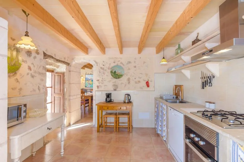 Una cocina luminosa con vigas de madera a la vista y una mesa en el centro.