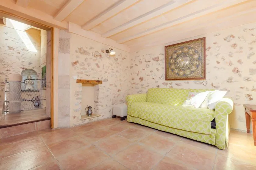 Una sala de estar con un sofá verde estampado y un cuadro enmarcado.