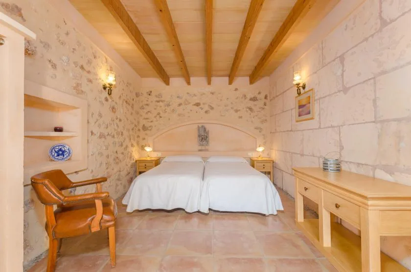 Un dormitorio con una cama, vigas de madera en el techo y paredes de piedra.