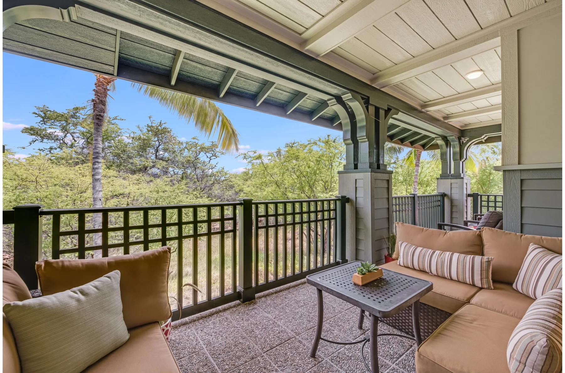 A covered outdoor seating area overlooks trees beyond a railing.